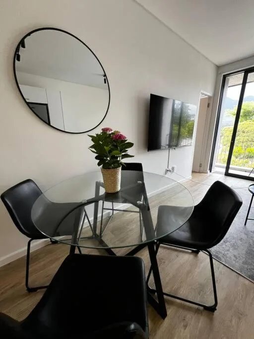 Modern lounge area with round mirror, glass dining table, and black chairs