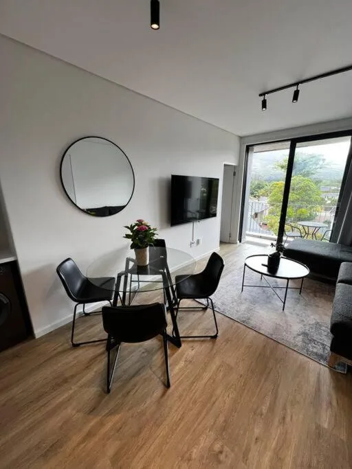 Modern lounge with dining chairs, round mirror, and mountain views
