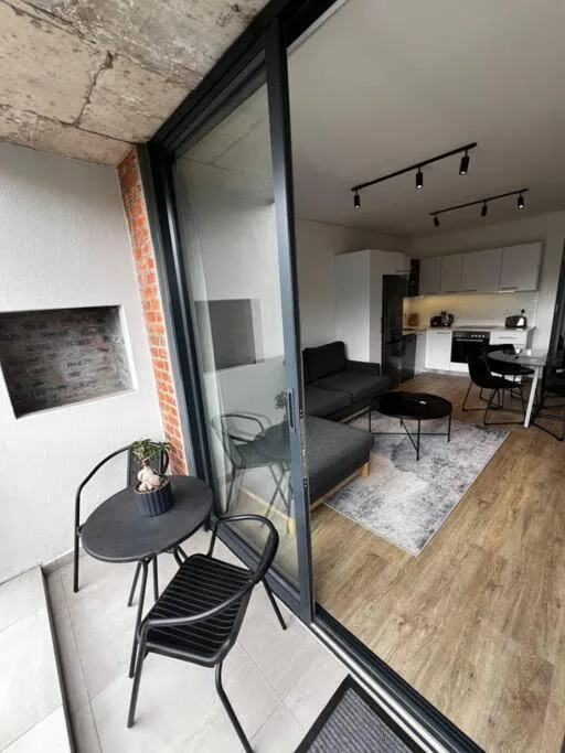 Modern open-plan lounge with black sofa, dining area, and kitchen visible beyond