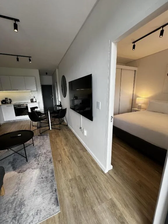 Modern open-plan lounge with flat-screen TV and kitchen visible