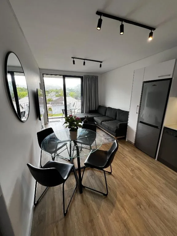 Modern lounge with dining table, sofa, and garden views through sliding doors