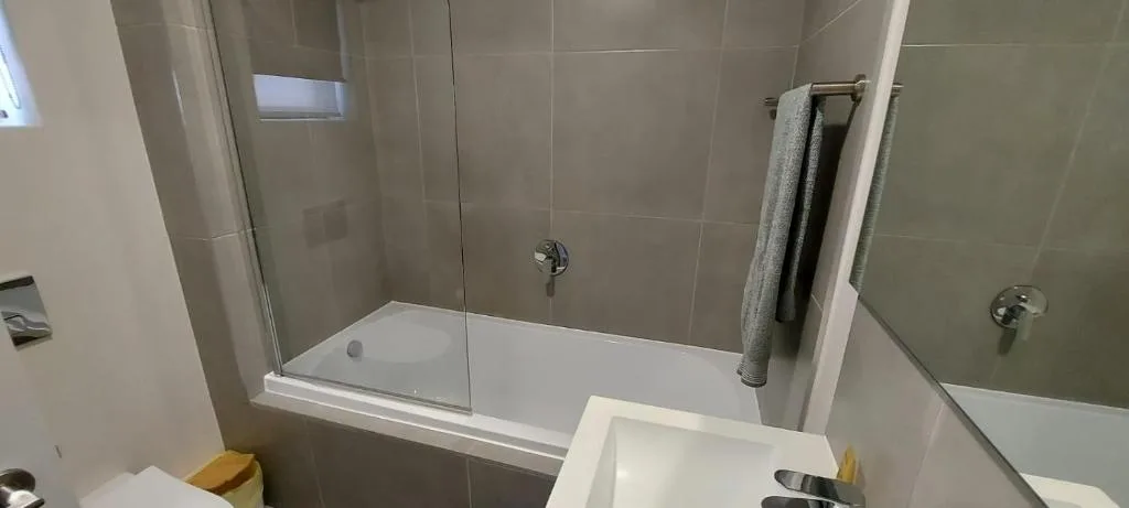 Modern bathroom with walk-in shower and grey tile walls