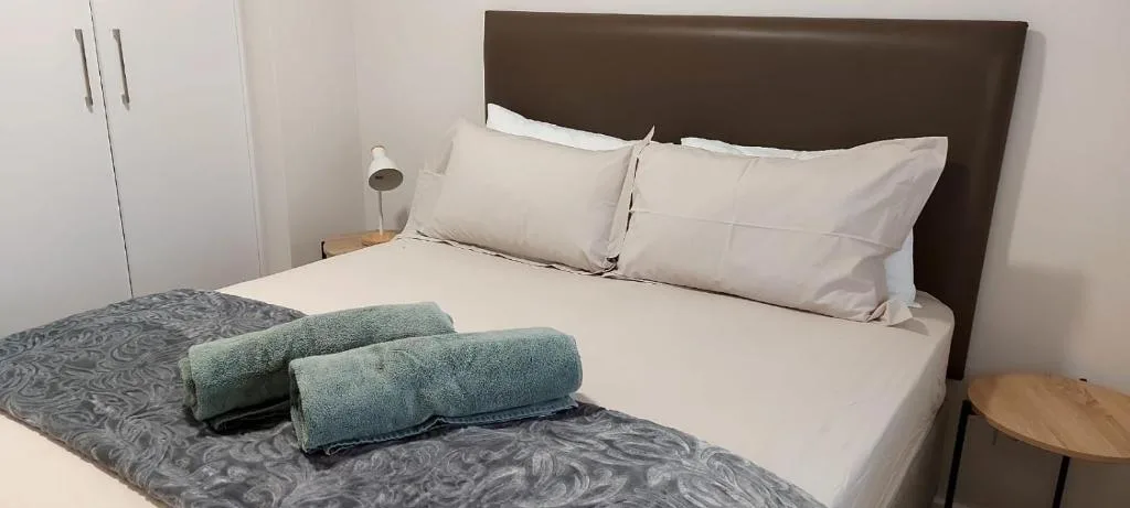 Neatly made bed with white linens and folded towels in modern bedroom