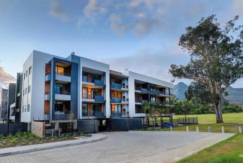 Modern multi-story apartment building with blue accents and mountain views