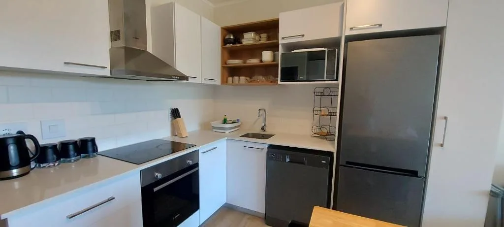 Modern kitchen with white cabinetry, stainless steel appliances, and open shelving