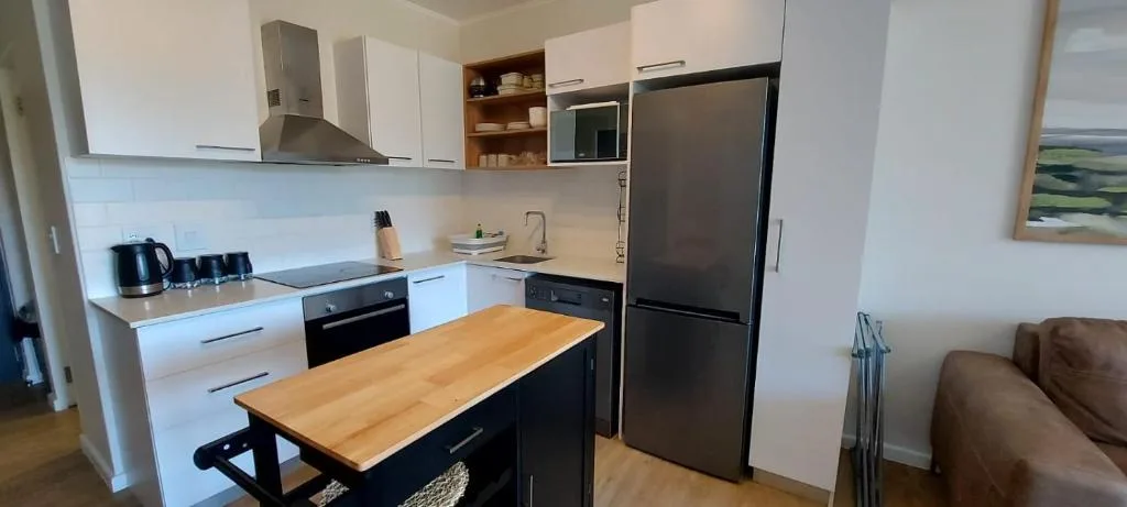 Modern kitchen with white cabinetry, black appliances, and wooden island counter