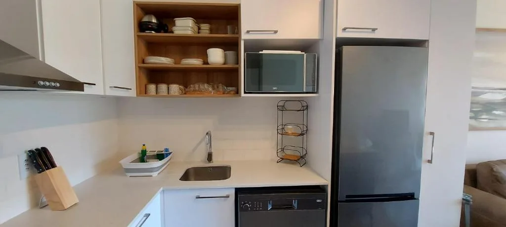 Modern kitchen with white cabinetry, stainless steel appliances, and open shelving