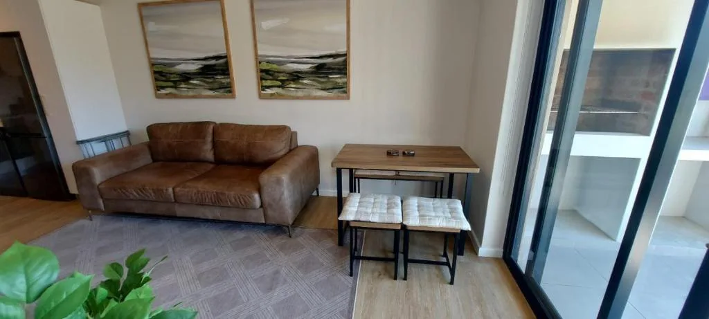 Modern lounge with brown leather sofa and side tables near windows