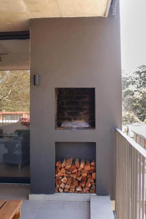 Modern outdoor fireplace with stacked firewood storage below cooking area
