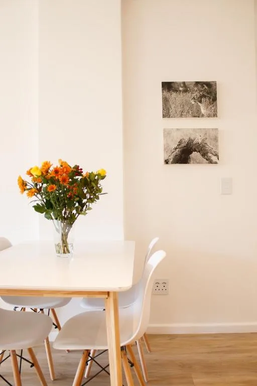 Bright dining area with white table, chairs, fresh flowers in vase