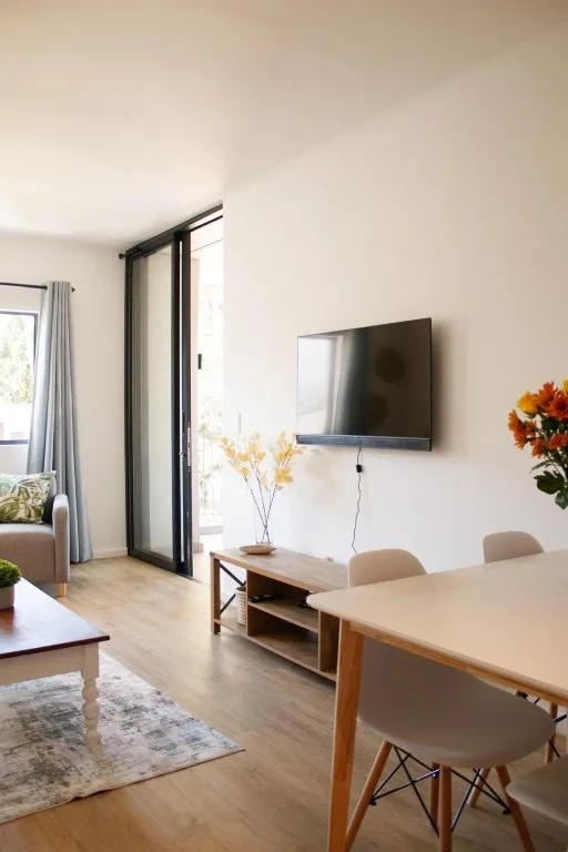 Open-plan lounge with dining table, TV, and glass doors to deck