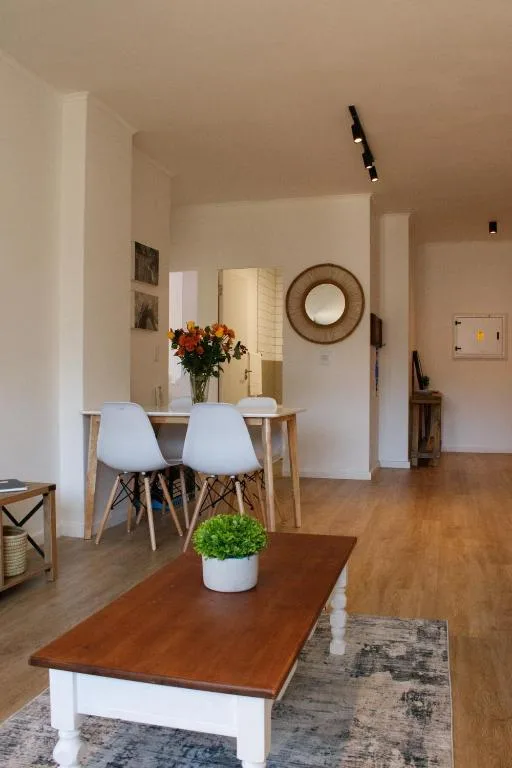 Open-plan living area with wooden table, white chairs, and decorative mirror