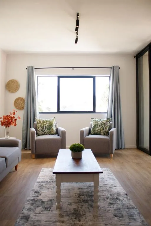 Bright lounge with grey armchairs, white coffee table, large windows