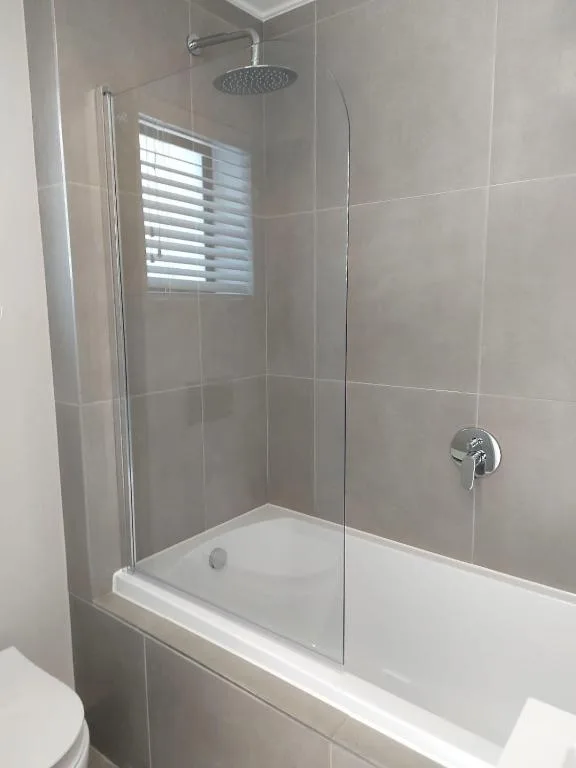 Modern bathroom with walk-in shower, glass enclosure, rainfall showerhead