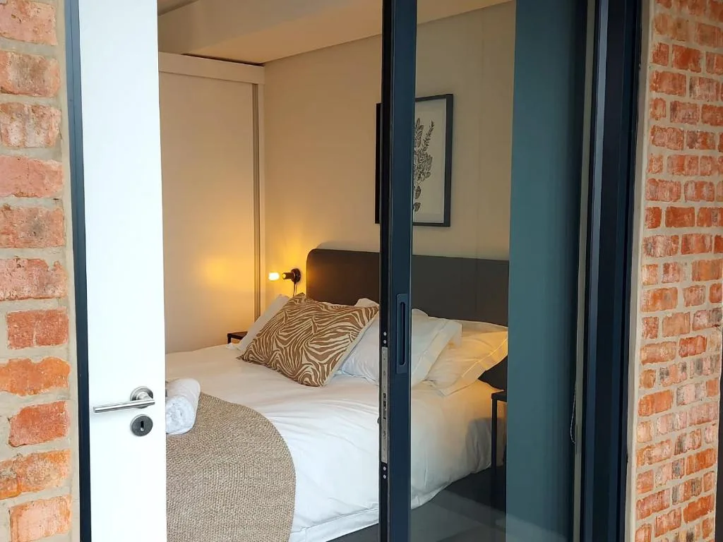 Modern bedroom with neatly made bed, zebra-print pillow, warm lighting