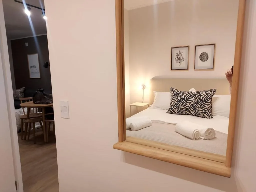 Modern bedroom with white bedding, zebra-striped pillow, and framed botanical wall art