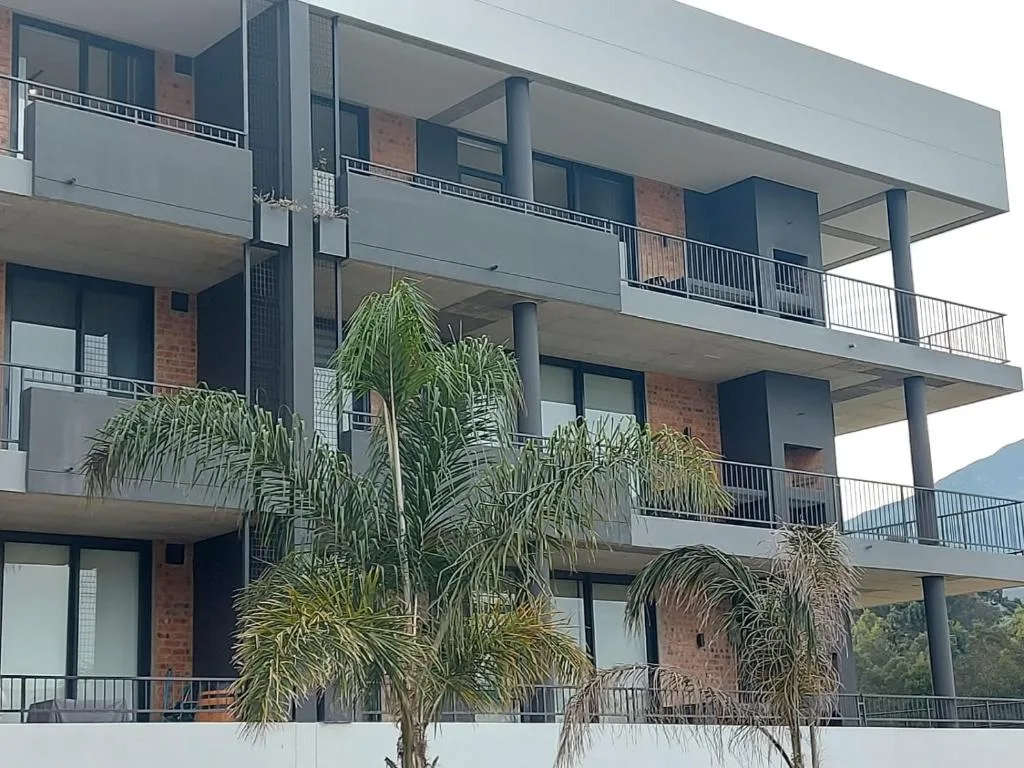 Modern multi-story apartment building with balconies and tropical palms