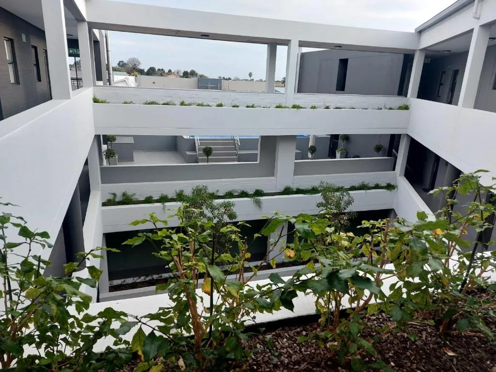 Modern white apartment building courtyard with tiered balconies and planted gardens