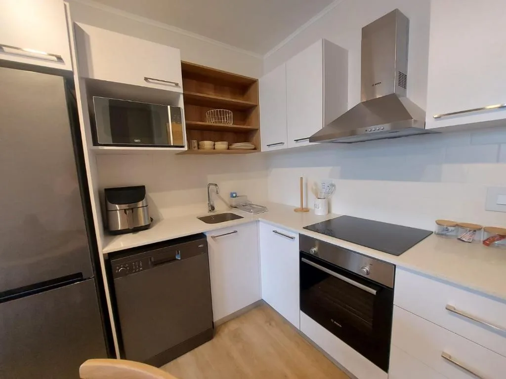 Modern kitchen with white cabinetry, stainless steel appliances, and wooden shelving.