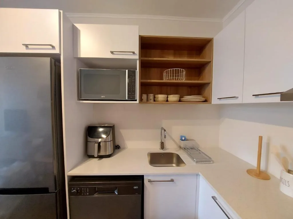 Modern kitchen with white cabinetry, stainless steel appliances, and wooden shelving