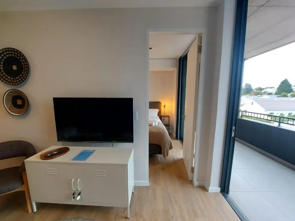 Modern lounge with wall-mounted TV, white storage cabinet, and sliding door to balcony