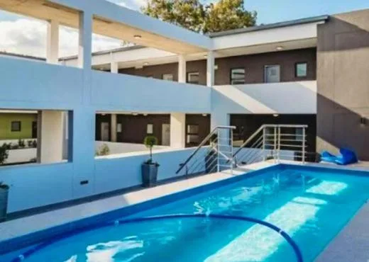 Bright blue swimming pool with modern house and deck area behind