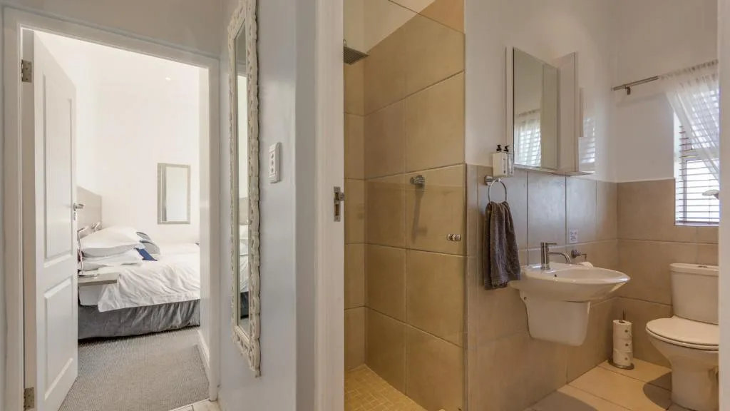 Ensuite bathroom with walk-in shower, vanity sink, and toilet adjacent to bedroom