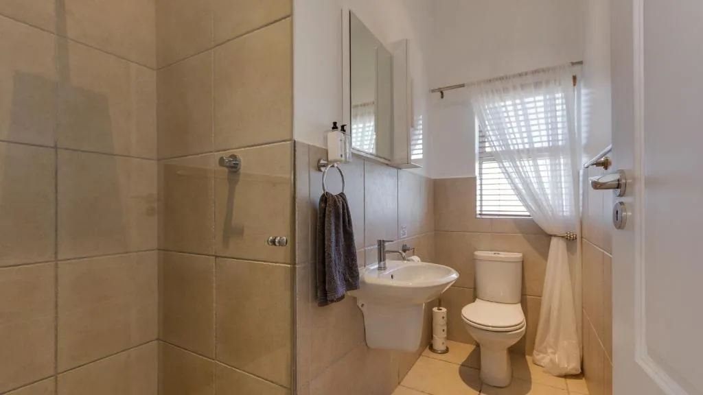 Clean bathroom with shower, sink, toilet, and bright window light