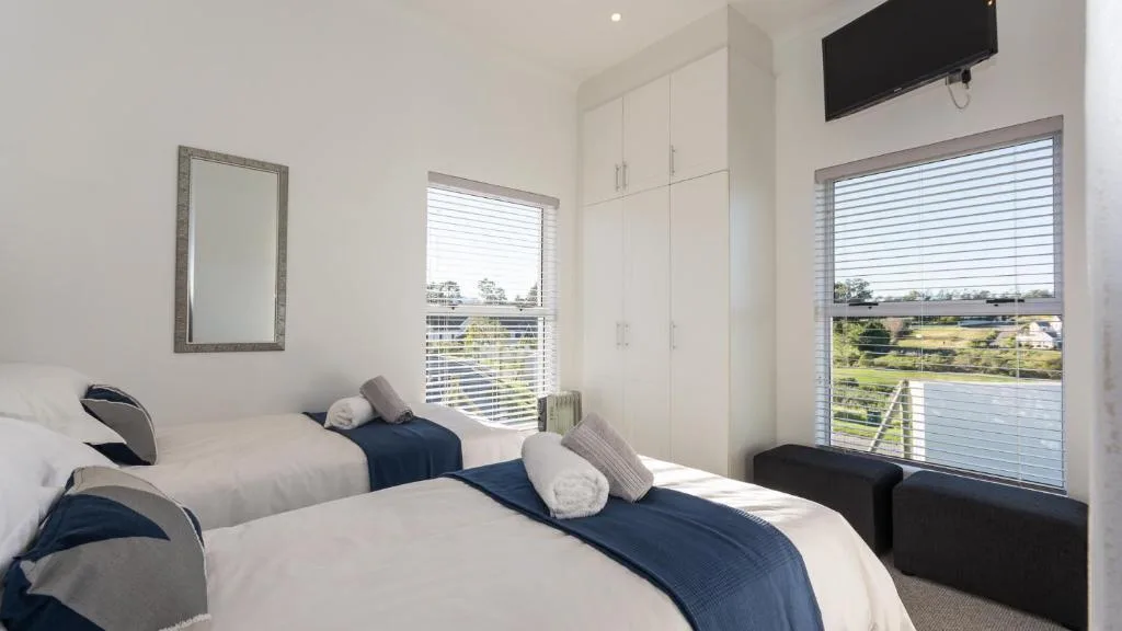 Modern bedroom with twin beds, white cabinetry, and scenic countryside views