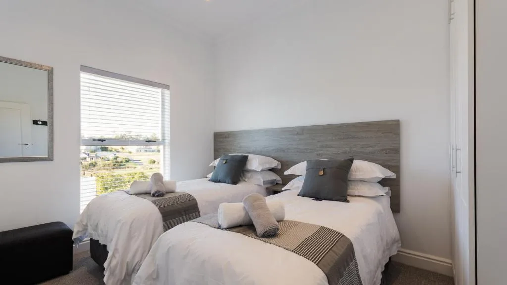 Bright bedroom with three single beds, wooden headboard, and garden view