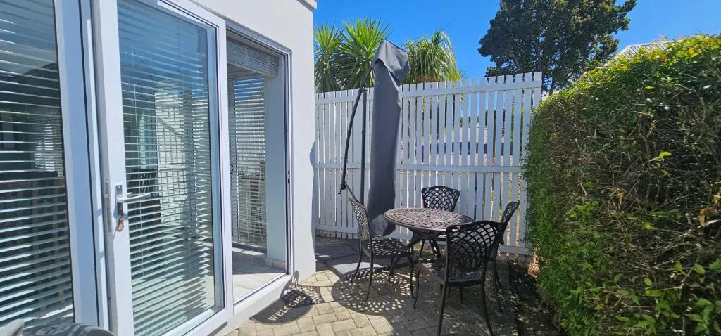 Patio with table, chairs, umbrella, and white fence surrounding