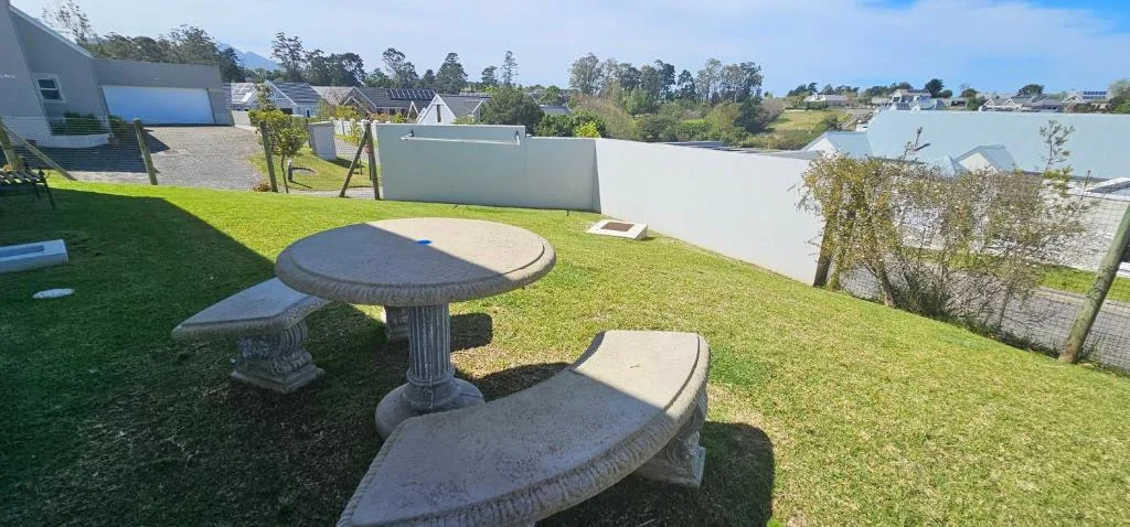 Outdoor garden area with stone table and benches on manicured lawn
