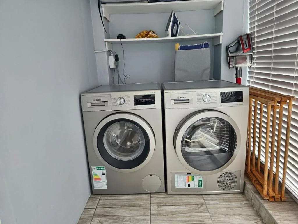 Modern laundry room with two Bosch washing machines and storage shelves