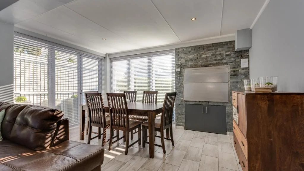 Dining area with wooden table and chairs, stone accent wall, and lounge seating