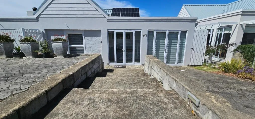 White modern house exterior with paved courtyard and potted plants