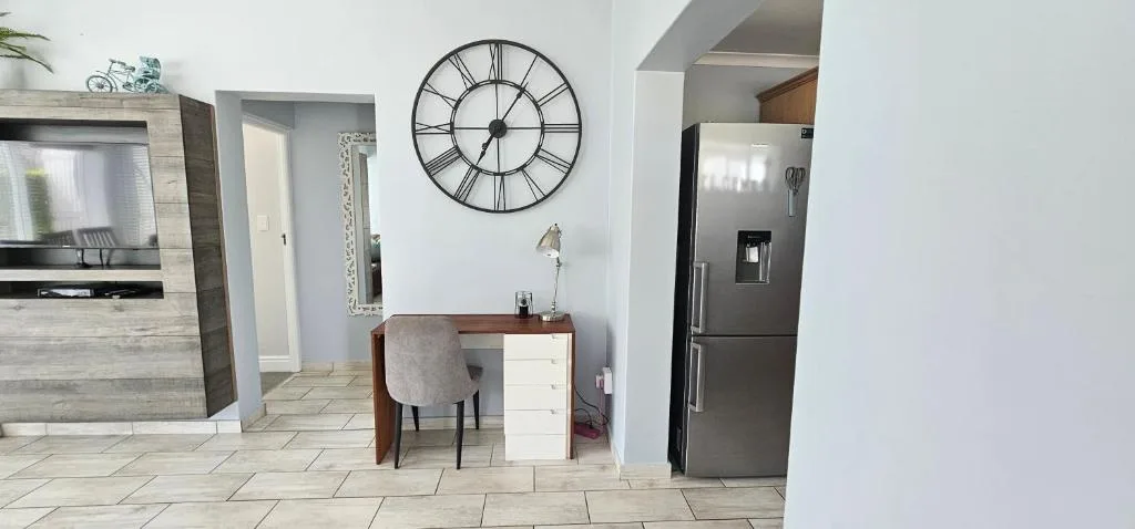 Modern kitchen with stainless steel fridge, desk area, and decorative wall clock