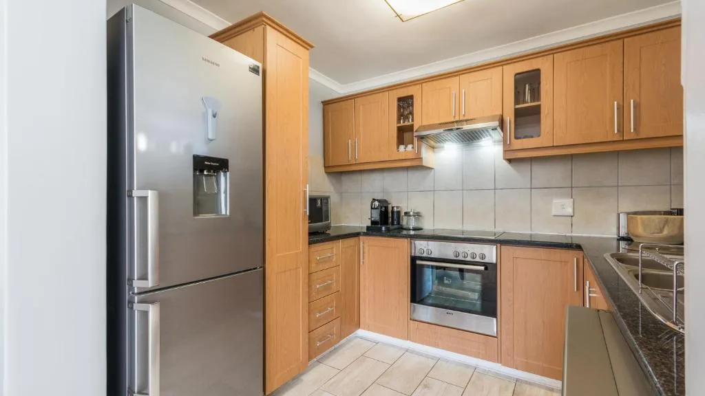 Modern kitchen with wooden cabinetry, stainless steel appliances, and dark countertops