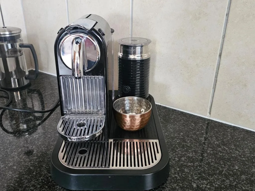 Nespresso coffee machine with milk frother on granite countertop