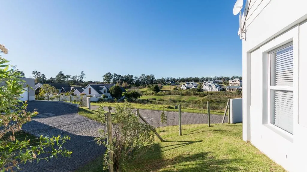 Expansive suburban vista with manicured garden, neighboring estates, and clear blue sky