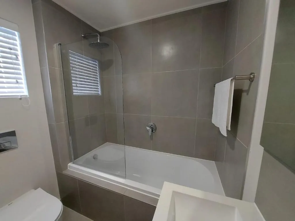 Modern bathroom with tiled shower enclosure and white bath tub