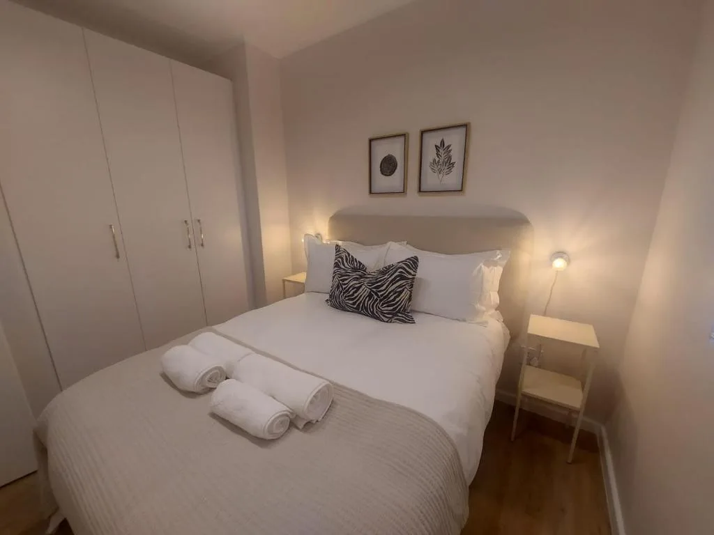 Modern bedroom with queen bed, fresh white linens, and rolled towels