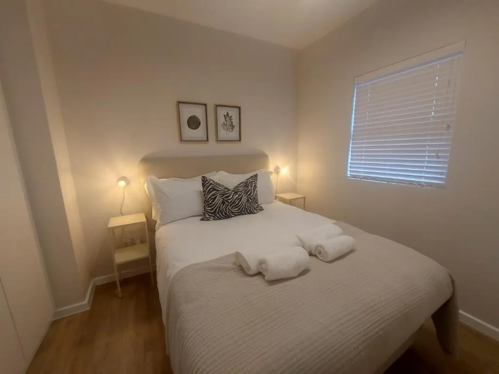 Bright bedroom with queen bed, fresh white linens, and warm bedside lighting