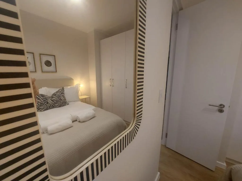 Modern bedroom with built-in bed, white bedding, striped accent wall, and storage cupboards