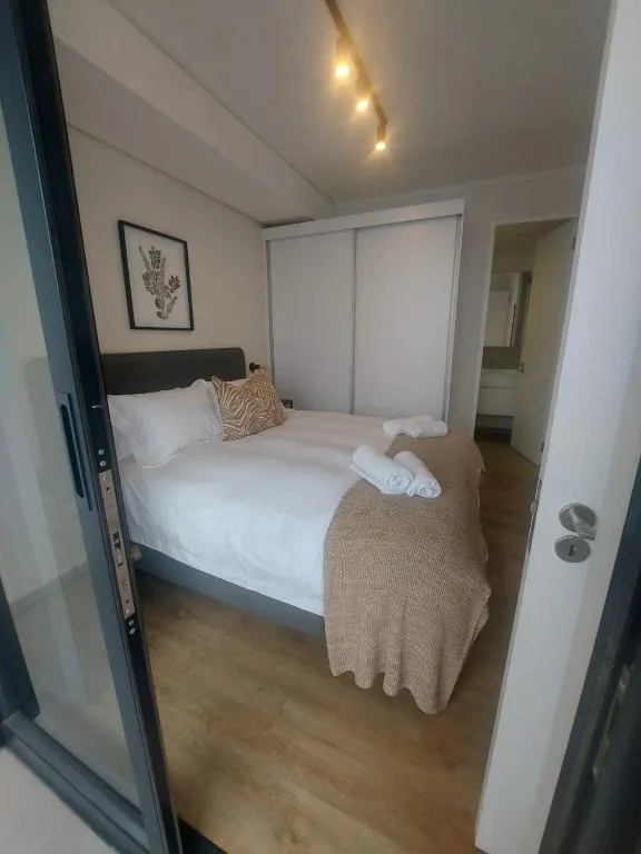 Bright bedroom with queen bed, white bedding, and modern built-in wardrobe