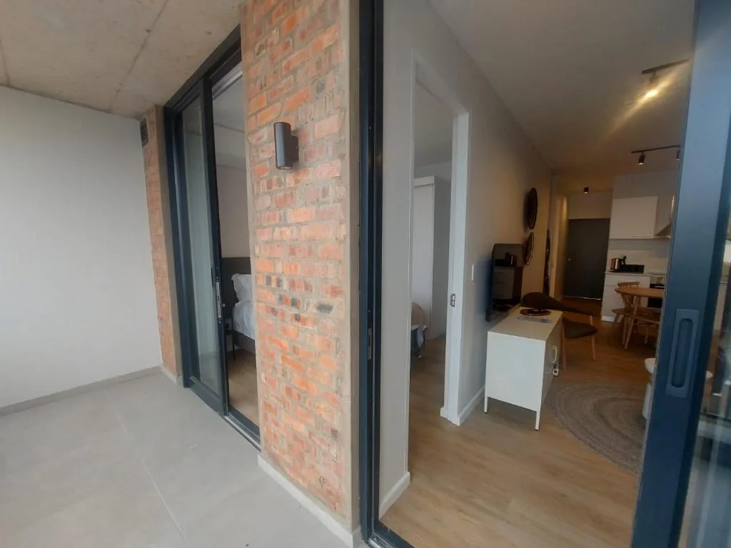 Modern apartment hallway with exposed brick wall and sliding glass doors