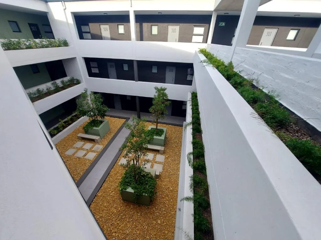 Modern white apartment building with central courtyard garden and landscaping