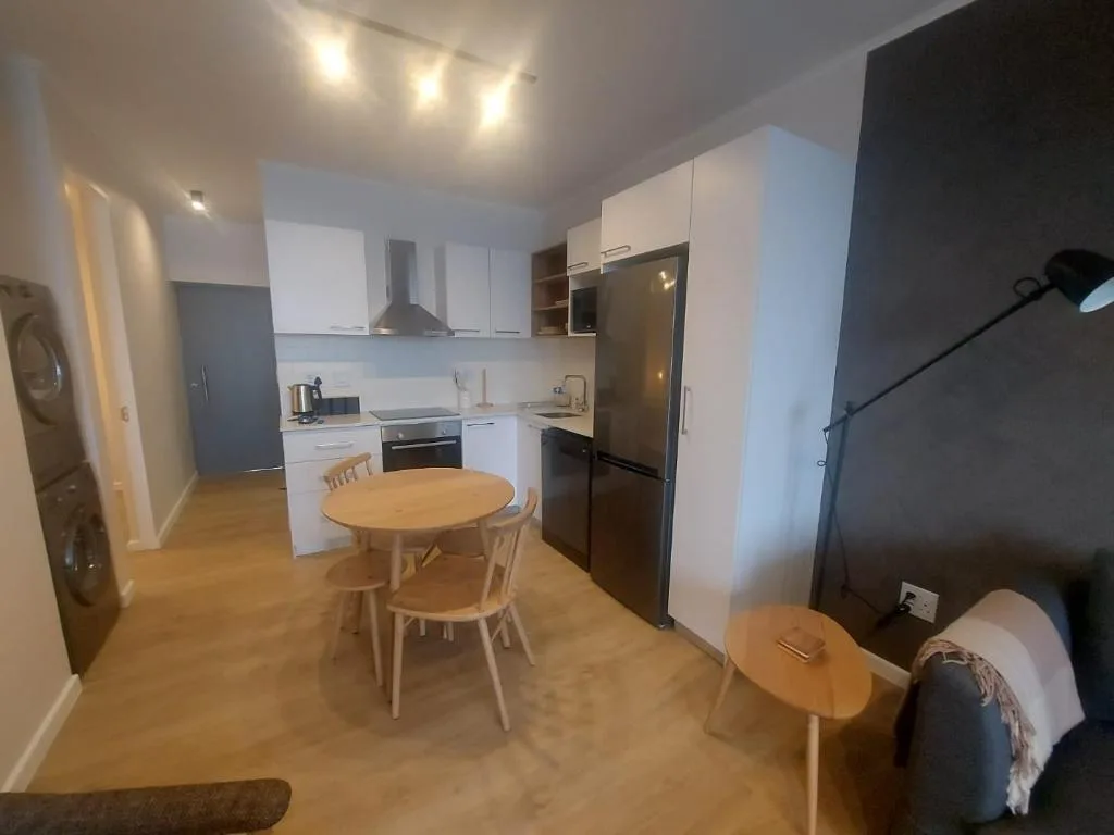 Modern kitchen with white cabinetry, black appliances, and dining table
