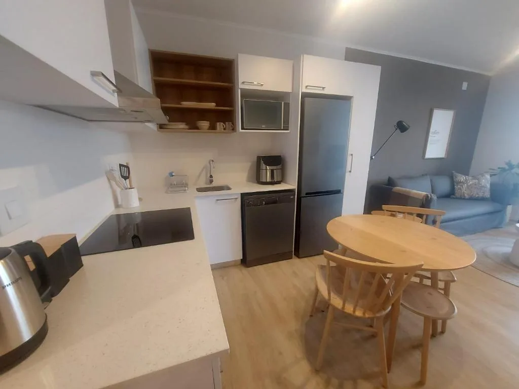 Modern kitchen with stainless steel appliances, white cabinetry, and dining table