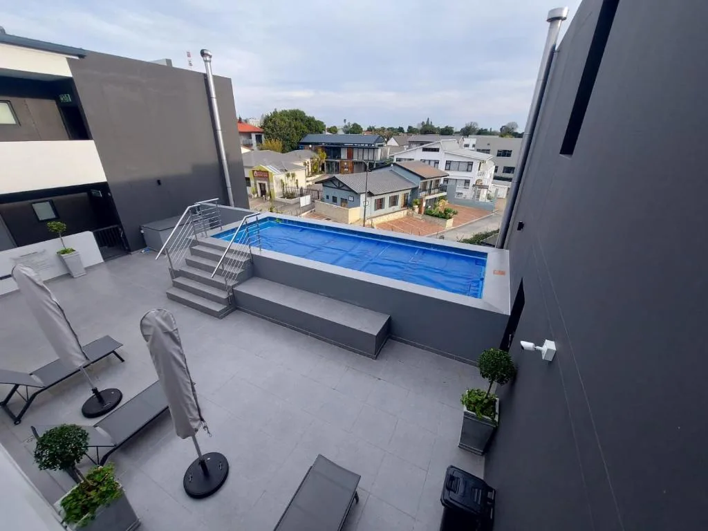 Rooftop swimming pool with loungers and neighborhood views