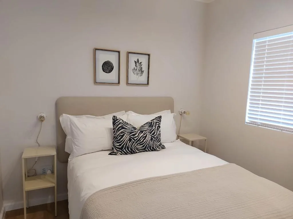 Bright bedroom with queen bed, neutral headboard, and zebra striped pillow accent